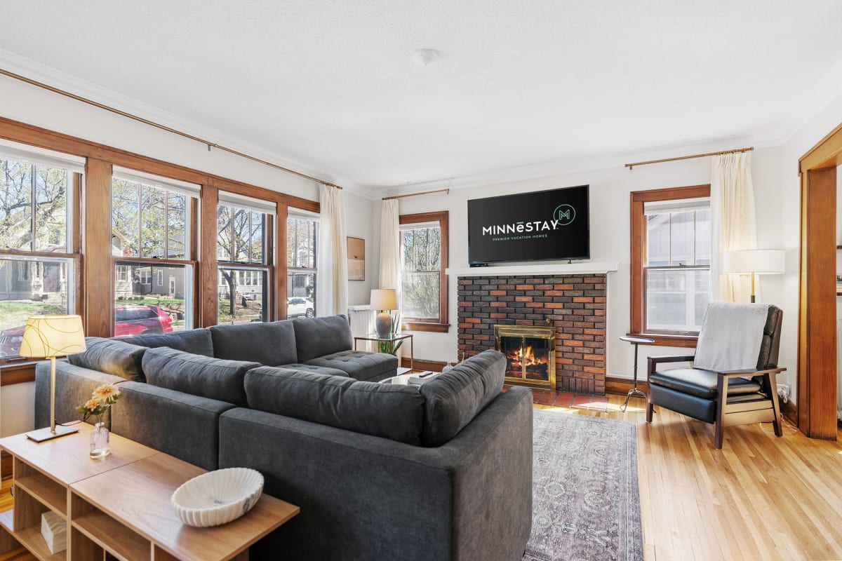 Cozy up by the crackling fireplace in your bright living room, where modern comfort meets classic charm with warm wood details.