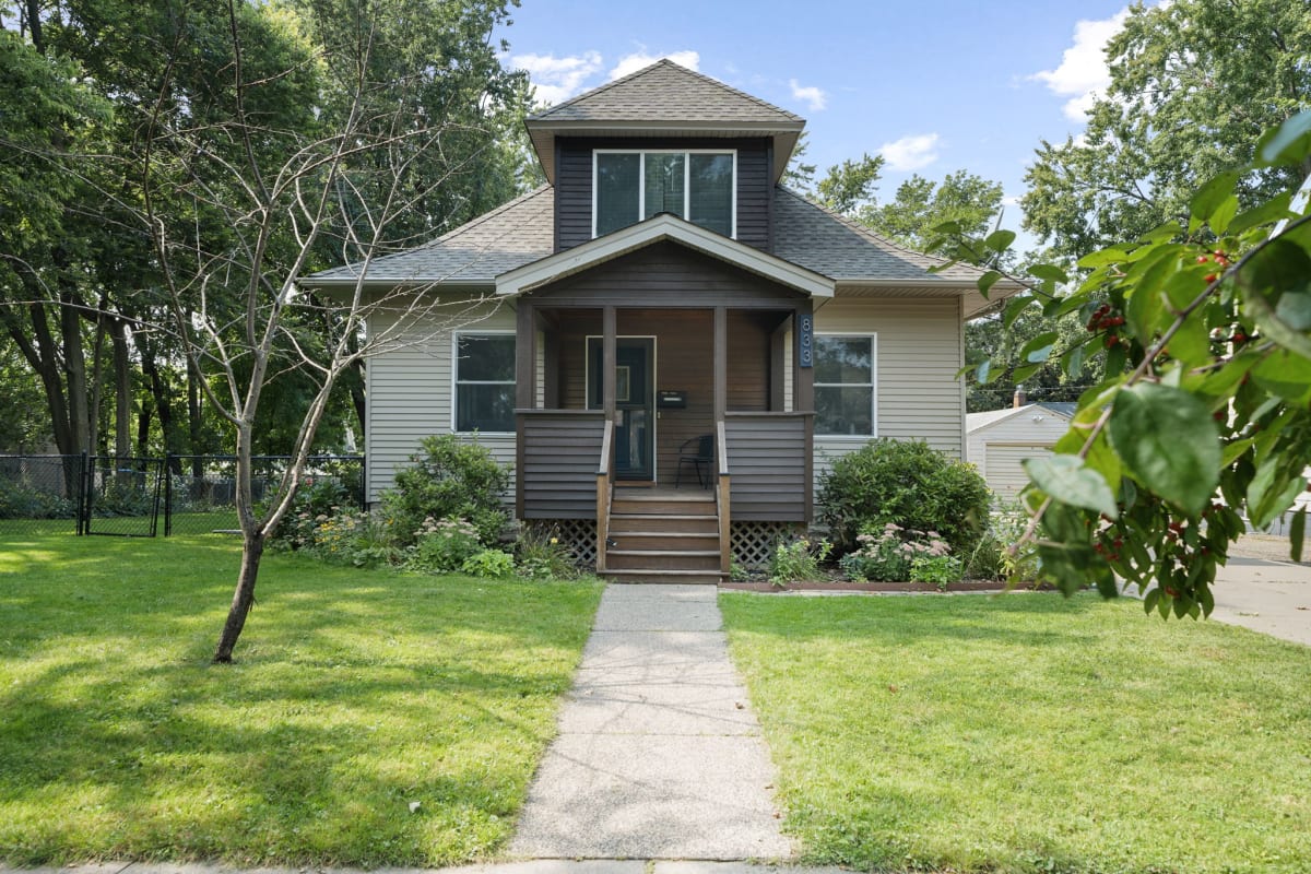 Charming craftsman-style home with welcoming front porch and manicured landscaping in a peaceful residential setting.