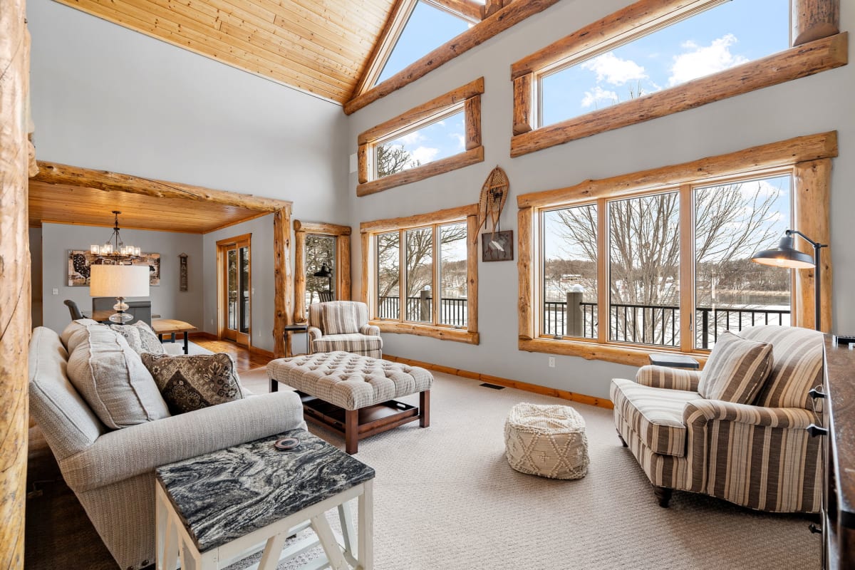 Relax in your stunning living room with soaring timber beams and panoramic windows showcasing snowy winter landscapes.