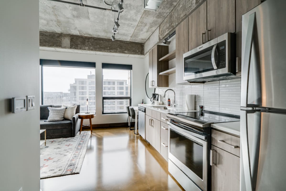 Your modern loft features a sleek kitchen with stainless steel appliances and warm wood accents, plus a cozy seating area by city-view windows.