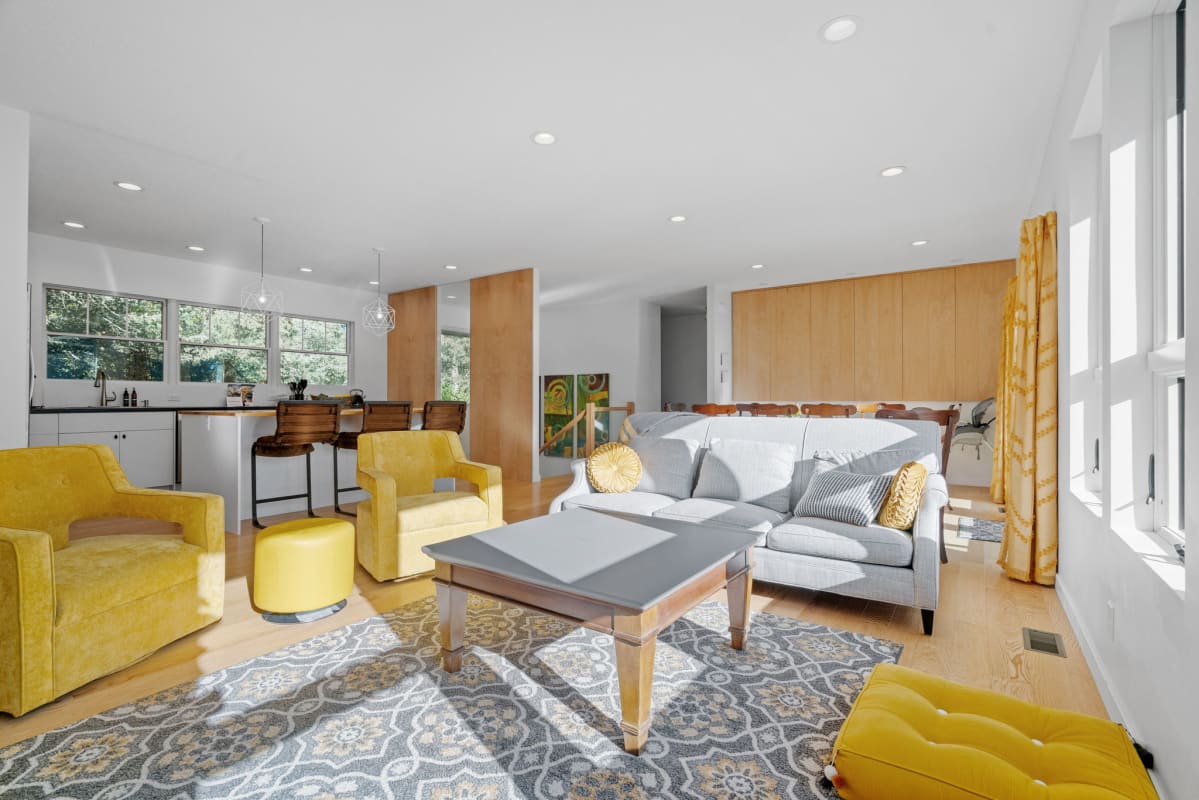 Unwind in this bright open living space where vibrant yellow chairs and sleek modern design create your perfect relaxation haven.