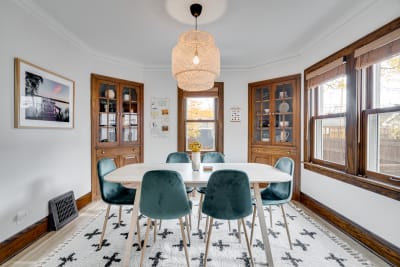 Cozy dining room with a round table, teal chairs, and woven pendant light.