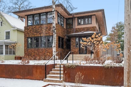 Modern two-story home made of brick with winter landscape featuring snow and dried plants.