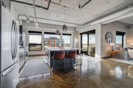 Modern open-concept kitchen and living area with high-end finishes and views of the city.