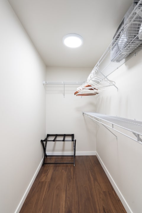 Interior view of a minimalist closet with wire shelves and a stool.