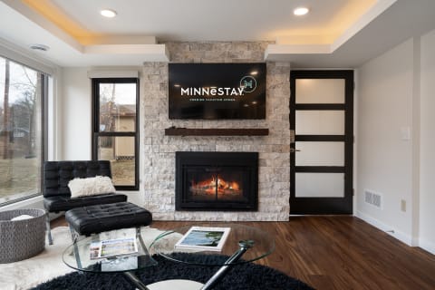 Modern living room with a fireplace and a television mounted on stone wall.