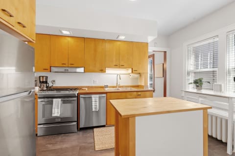 Interior view of a modern kitchen featuring wooden cabinets and stainless steel appliances.