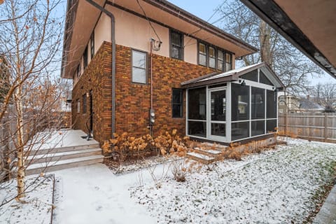 Two-story house with brick exterior and screened porch in winter scenery.