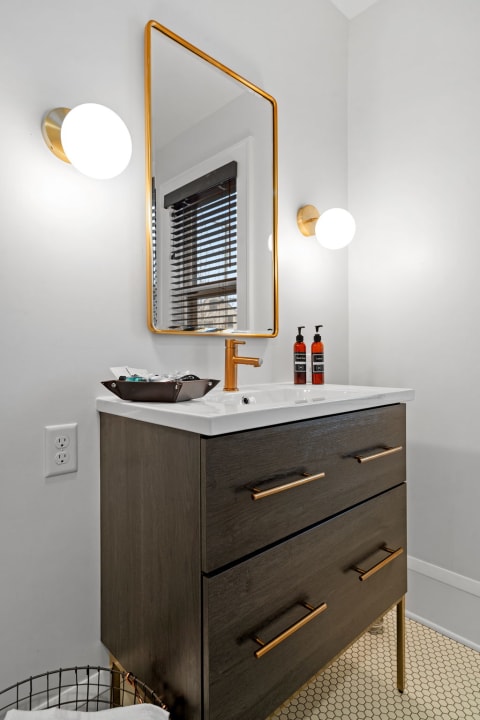 Stylish bathroom with a wooden vanity and gold-framed mirror.
