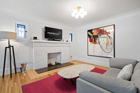 Modern living room with a gray sofa, pink rug, and abstract art.
