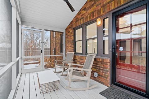 Interior view of a sunroom featuring rocking chairs and a wooden coffee table.
