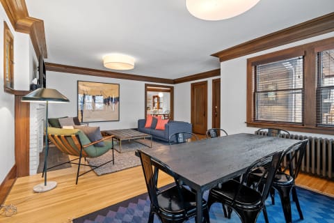 Stylish living room with a green chair, blue couch, dining table, and abstract art.