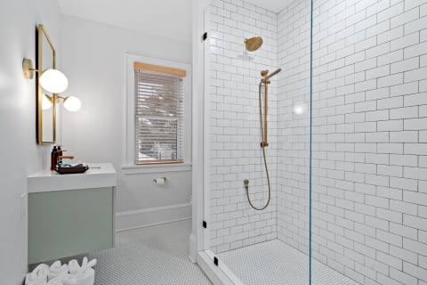 Contemporary bathroom with glass shower, white subway tiles, and elegant brass fixtures.