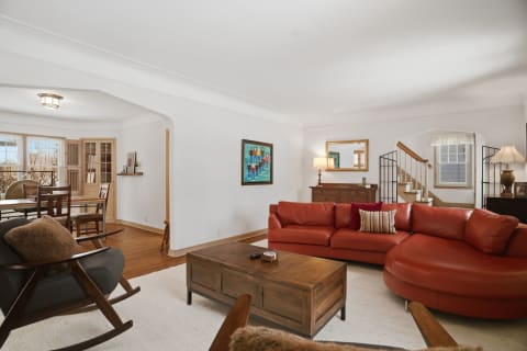 Spacious living room with leather sectional, wooden coffee table, and dining area in the background.