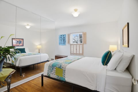 Bright bedroom featuring a colorful quilt, modern furnishings, and warm wooden floors.