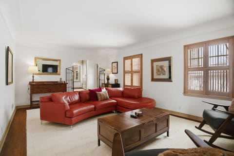 Spacious living room featuring a coral leather sofa, wooden accents, and bright windows.