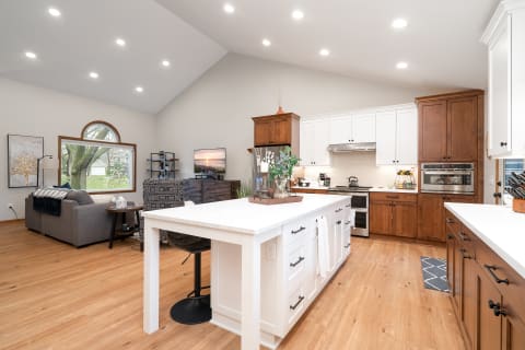 A spacious kitchen and living area featuring wooden cabinetry, a white island, and comfortable furnishings.