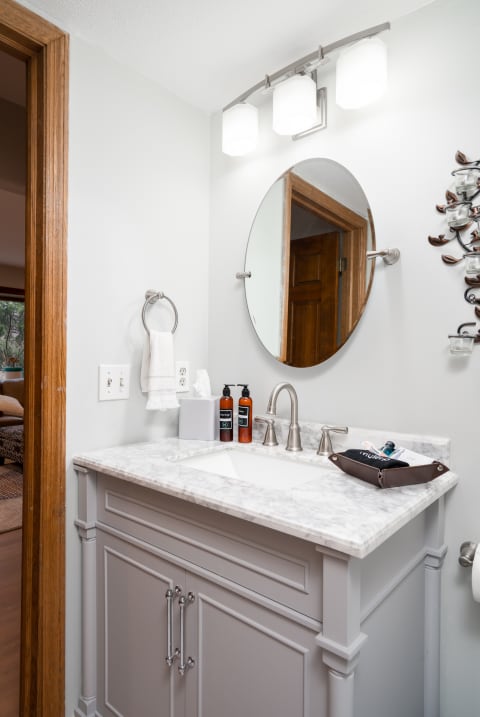 Modern bathroom with gray vanity, marble countertop, and elegant lighting.