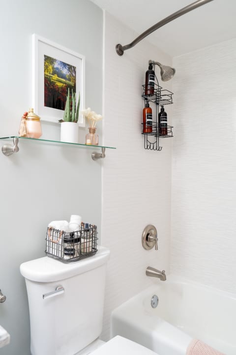 A well-organized modern bathroom featuring a toilet, shower area, and decorative items on shelves.