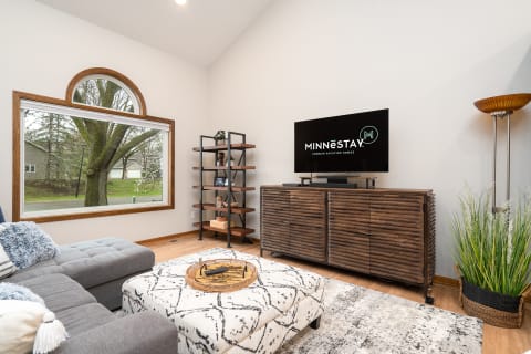 Spacious living room with gray sectional sofa, wooden cabinet, and decorative elements.