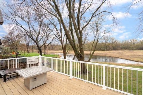 Wooden deck with a table and bench overlooking a serene river and landscape.