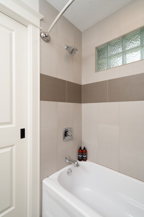 Modern bathroom corner with a white bathtub, chrome faucet, and decorative bottles.