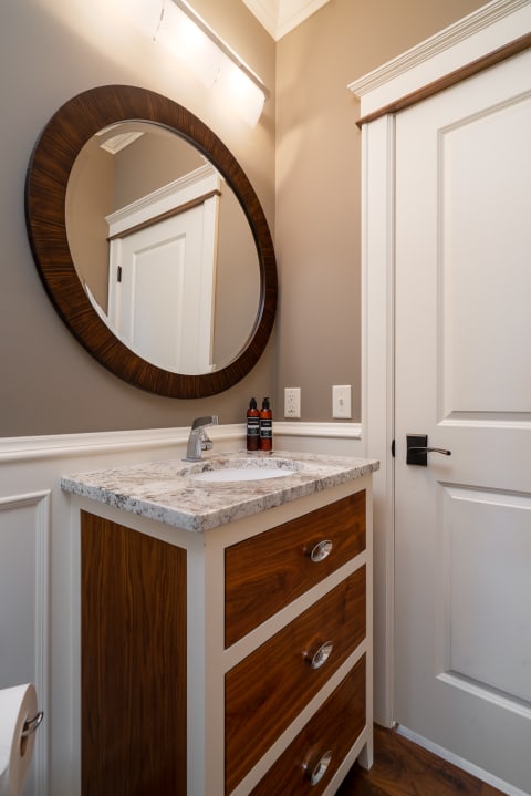 Modern bathroom with a round mirror and wooden vanity.