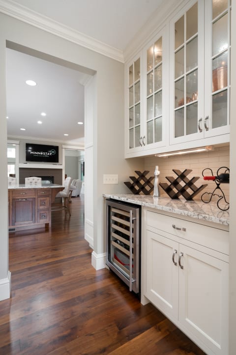 Interior photo of a modern kitchen featuring white cabinetry and dark hardwood flooring.