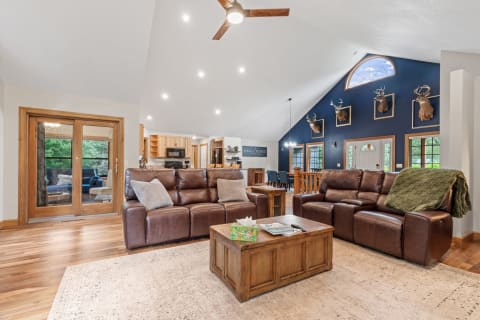 Spacious living room with vaulted ceiling, leather sofas, and wooden accents.