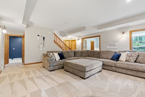 A spacious living room with a large gray sectional sofa, decorative pillows, and wooden accents.