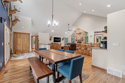 Interior view of a cozy open-concept living area with a dining table and stone fireplace.