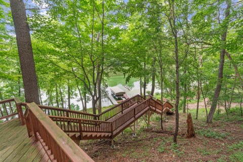 Wooden staircase surrounded by trees, leading to a lake with a dock.