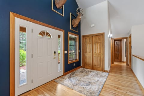 A cozy entryway showcases a white door, wooden accents, and deer mounts against a blue wall.