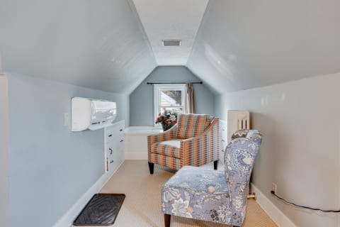 An inviting attic space with sloped walls, featuring two chairs and a window.