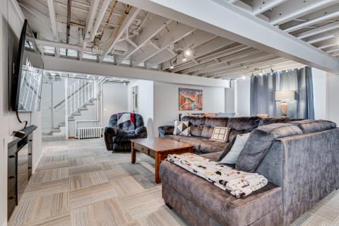 A spacious and inviting basement living room featuring a gray sectional sofa, wooden coffee table, and decorative elements.