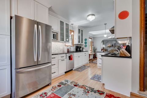 Modern kitchen featuring stainless steel appliances, white cabinetry, and decorative elements.