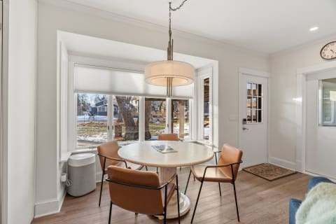 Bright breakfast nook with a round table and leather chairs beside large bay windows.