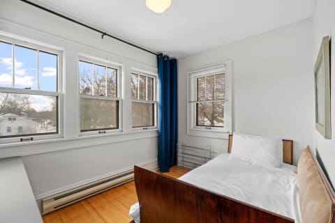 Bright bedroom with large windows, a bed, and blue curtains.