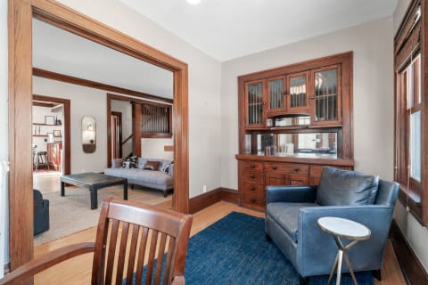 Interior of a stylish living space with a blue leather chair, wooden cabinet, and gray sofa.