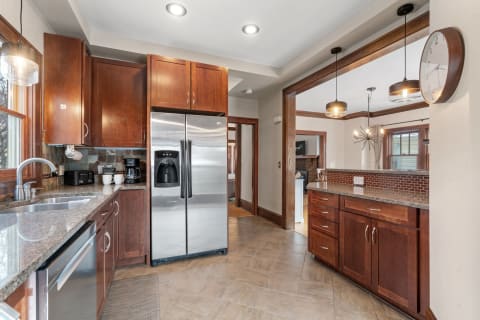 A cozy modern kitchen with dark wood cabinets, stainless steel refrigerator, and granite countertops.