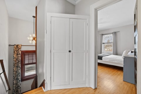 Interior view of a staircase landing with a modern light fixture and doorway to a bedroom.