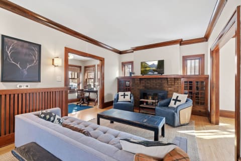 Cozy living room featuring a light blue sofa, brick fireplace, and natural light from windows.