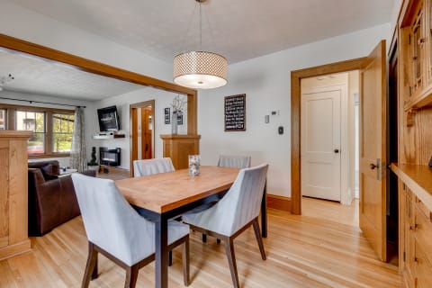 Cozy dining area with wooden table and grey chairs opening into a living room.