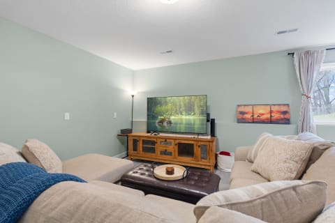 Cozy living room featuring a sectional sofa, a television with nature scenery, and rustic wooden furniture.