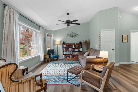 Stylish living room with a brown leather sofa, large windows, and a colorful rug.