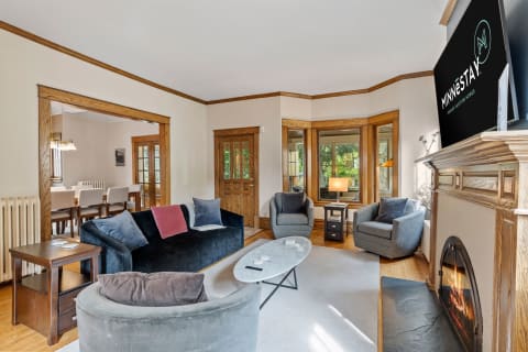 Cozy living room with black sofa, gray chairs, and a fireplace.
