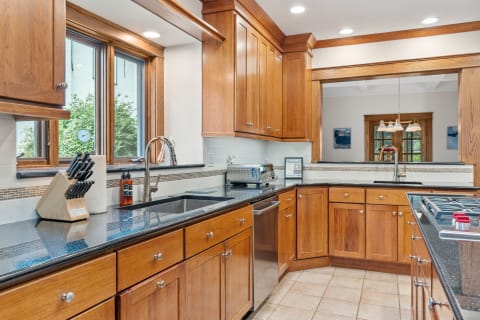Modern kitchen with wooden cabinets, black granite countertops, and stainless steel appliances.