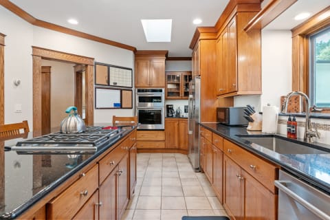 Bright kitchen with wooden cabinets and a central island, featuring a kettle and modern appliances.
