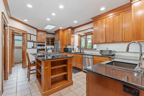 Interior of a modern kitchen showing wooden cabinets and an island with granite surface.
