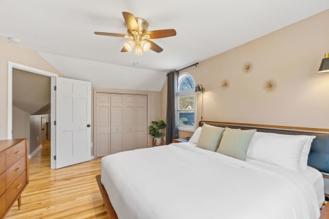 Cozy bedroom with a large window, neatly made bed, and stylish decor.
